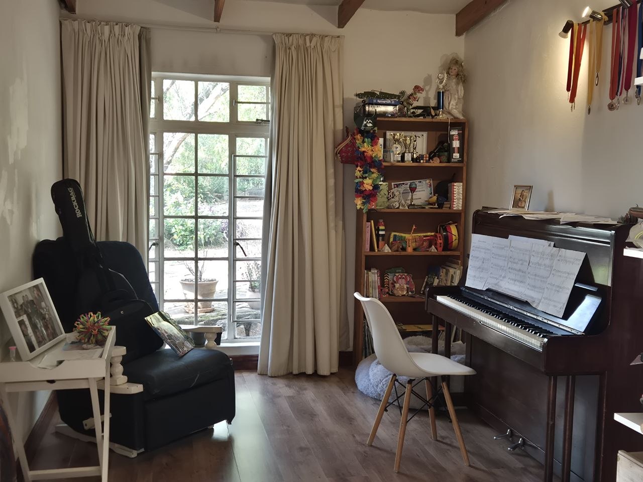 Musikzimmer mit Klavier, Gitarre und Bücherregal