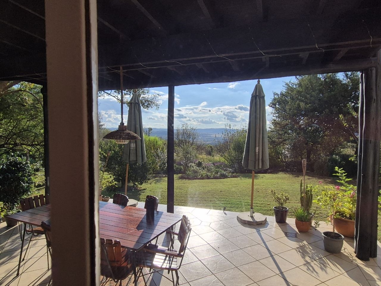 Überdachte Terrasse mit Holztisch und Blick über den Garten