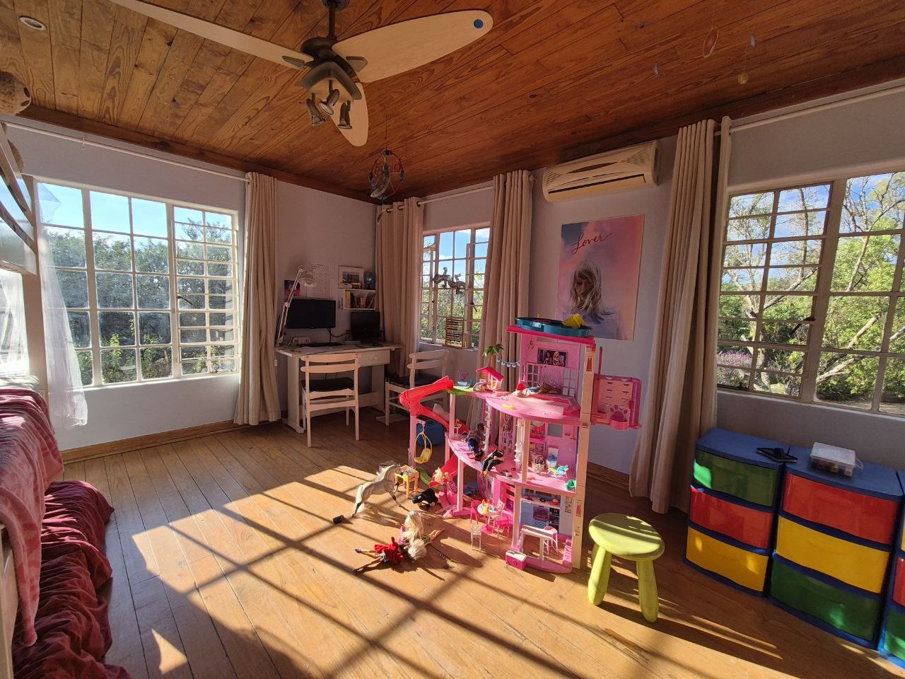 Helles Kinderzimmer mit Spielsachen, Holzdecke und großen Fenstern